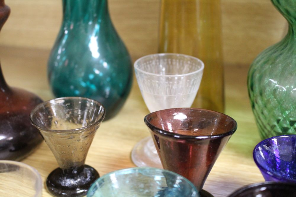 A collection of assorted coloured glassware including hyacinth vases, tallest 21cm